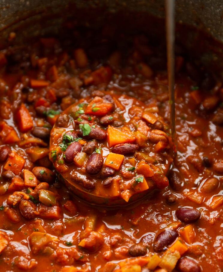 close up shot of ladle scooping up veggie chilli in large pot