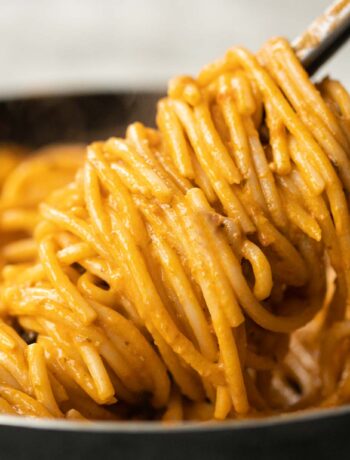 close up shot of tongs twisting pasta in pan
