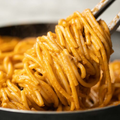 close up shot of tongs twisting pasta in pan