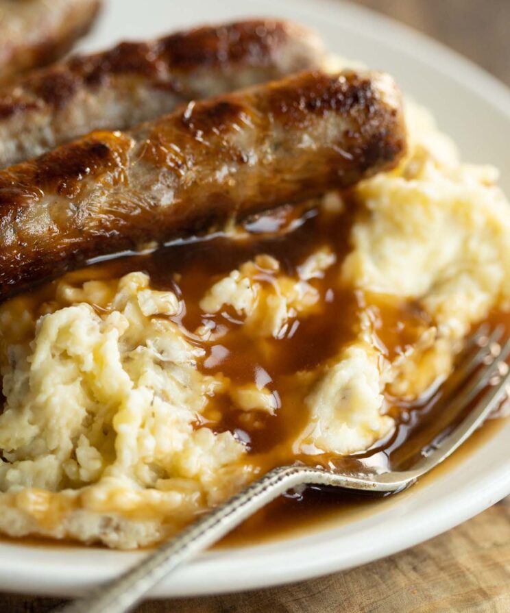 mashed potatoes and gravy on small white plate with small silver fork