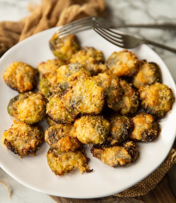 smashed brussels sprouts on small white plate with two silver forks