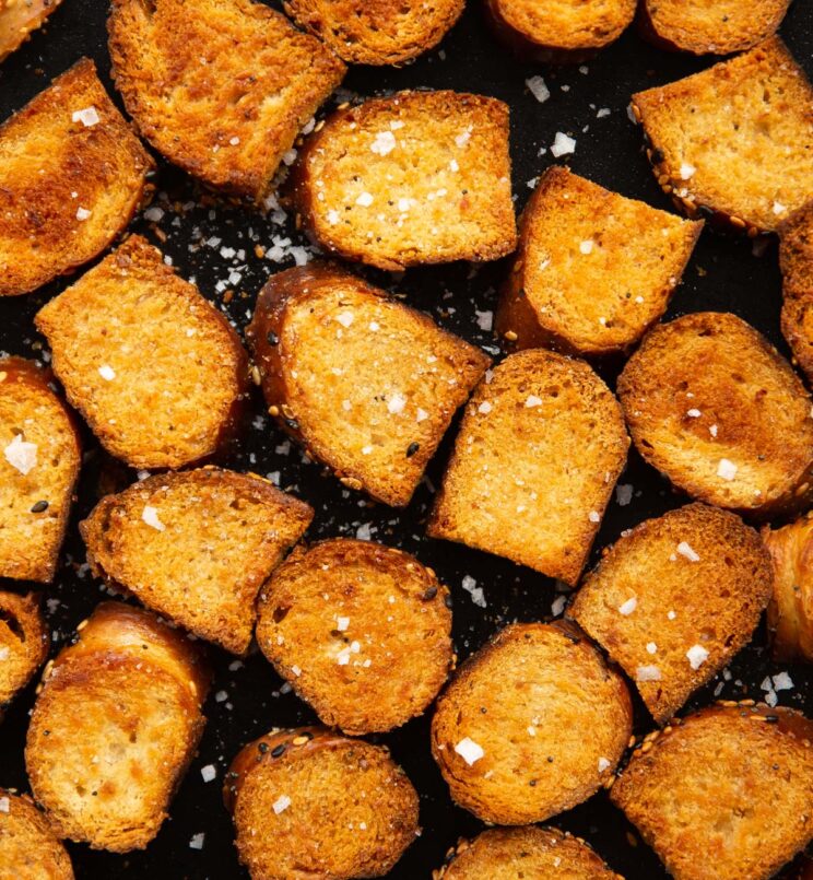 close up overhead shot of bagel chips fresh out the oven on black tray