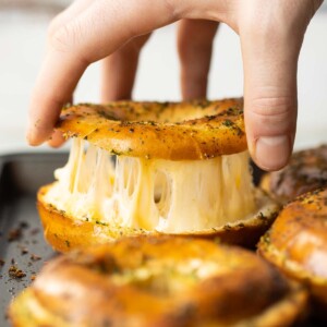 close up shot of hand lifting lid of bagel with cheese pull