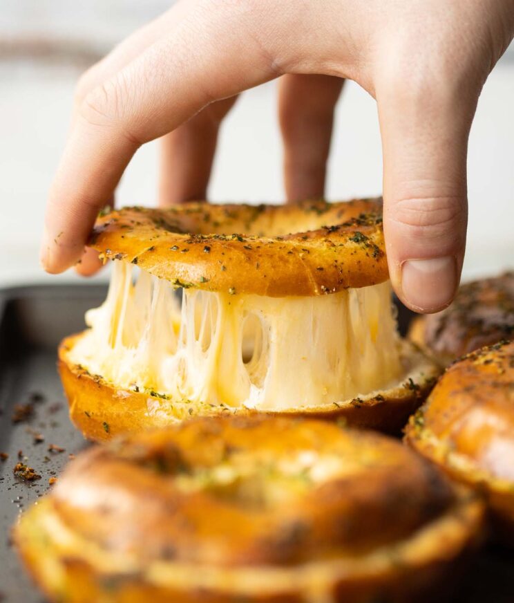 close up shot of hand lifting lid of bagel with cheese pull