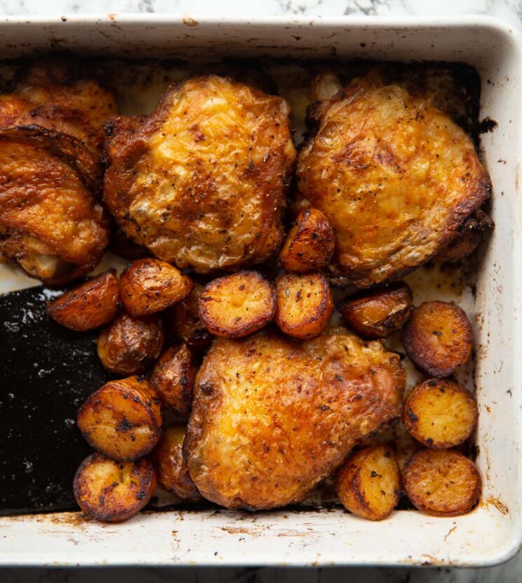 overhead shot oven baked chicken potatoes in large white baking dish