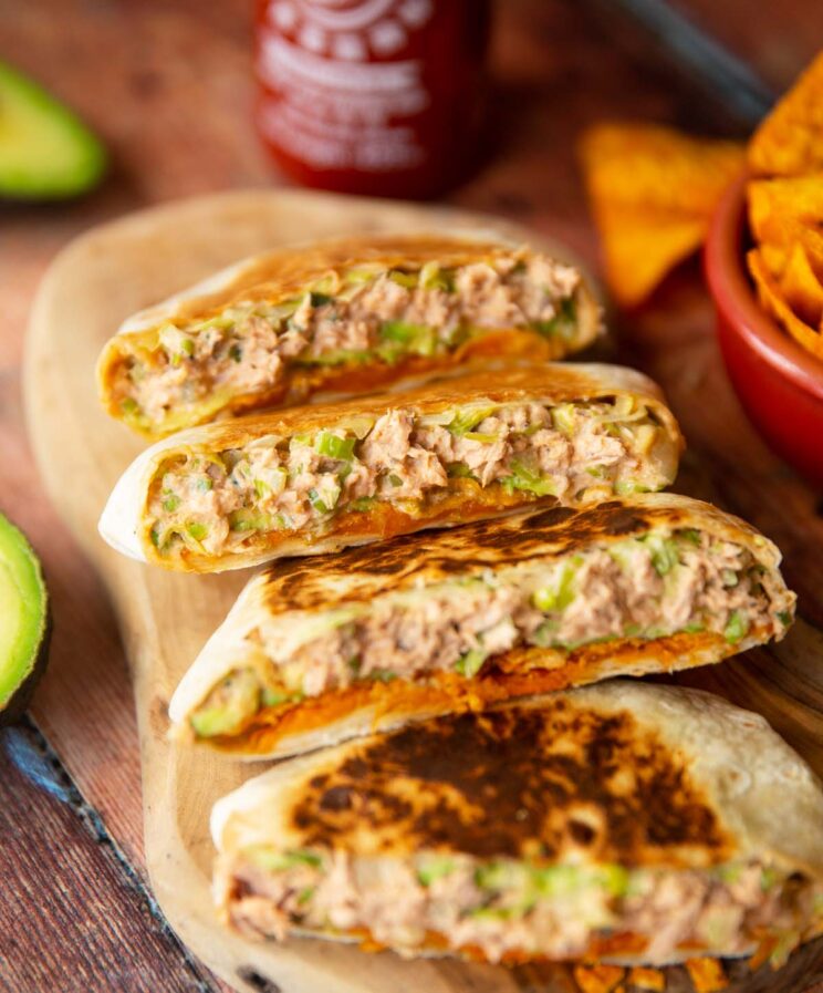 close up shot of spicy tuna crunchwraps sliced in half on wooden board