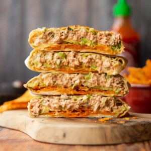 4 crunchwrap halves stacked on each other on wooden board showing filling