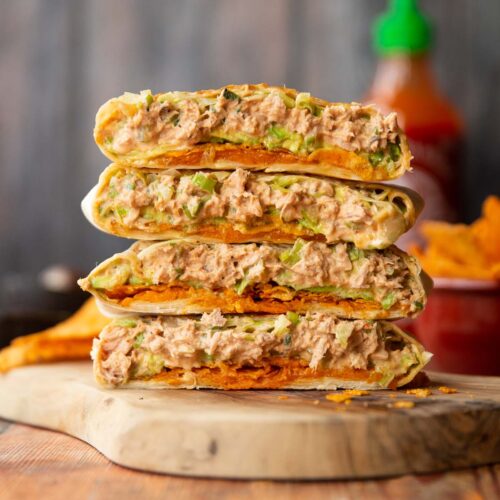 4 crunchwrap halves stacked on each other on wooden board showing filling