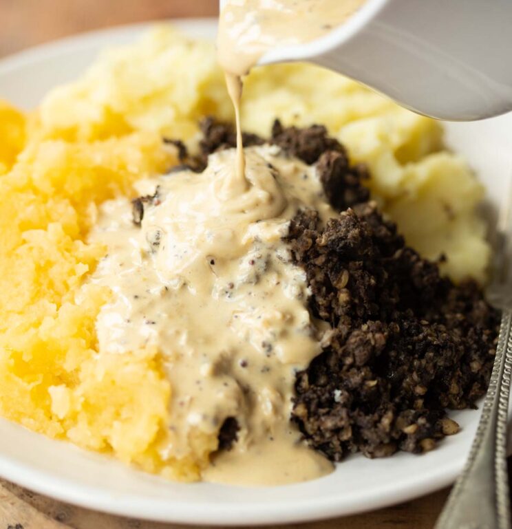close up shot of whiskey cream sauce and haggis on small white plate