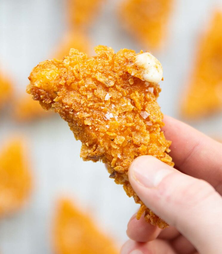 close up shot of fingers holding cheese stuffed Dorito with cheese spilling out the corner