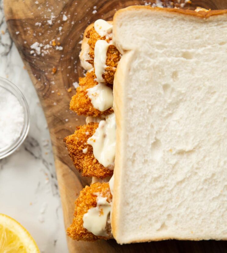 close up overhead shot of fish finger sandwich on wooden board