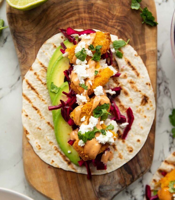 close up overhead shot of fish finger taco on wooden chopping board