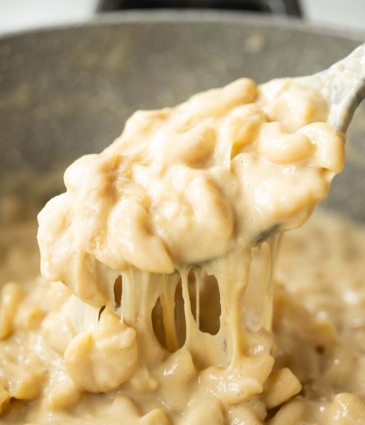 close up shot of serving spoon digging into pot of mac and cheese