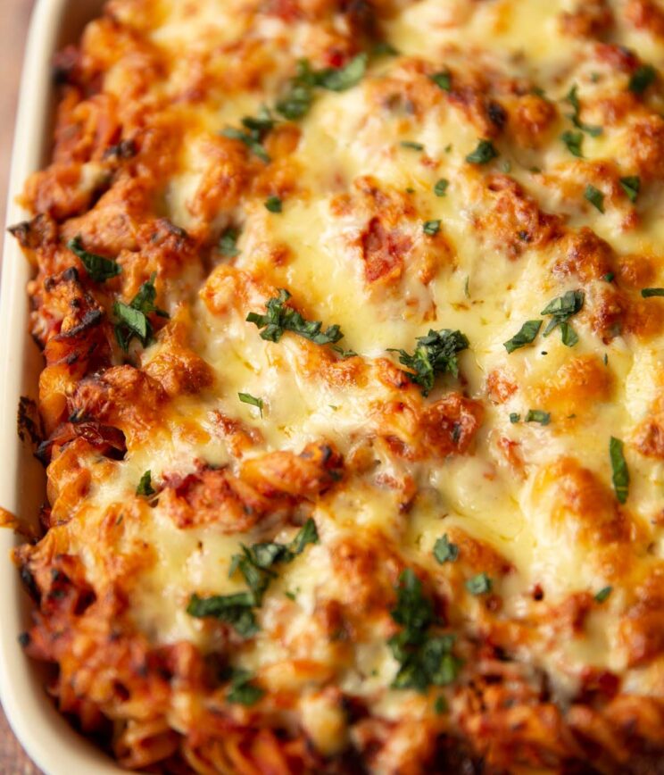 close up shot of cheese tomato tuna pasta bake fresh out the oven garnished with basil