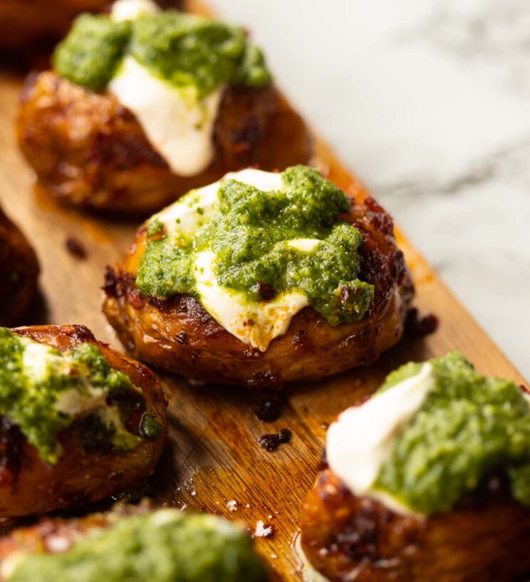 close up shot of pesto nduja potato on wooden chopping board