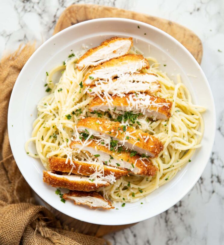 overhead shot of chicken kiev pasta served in a white dish on wooden chopping board