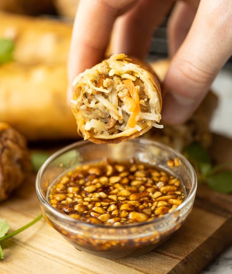 close up shot of hand holding half a Thai spring roll showing filling