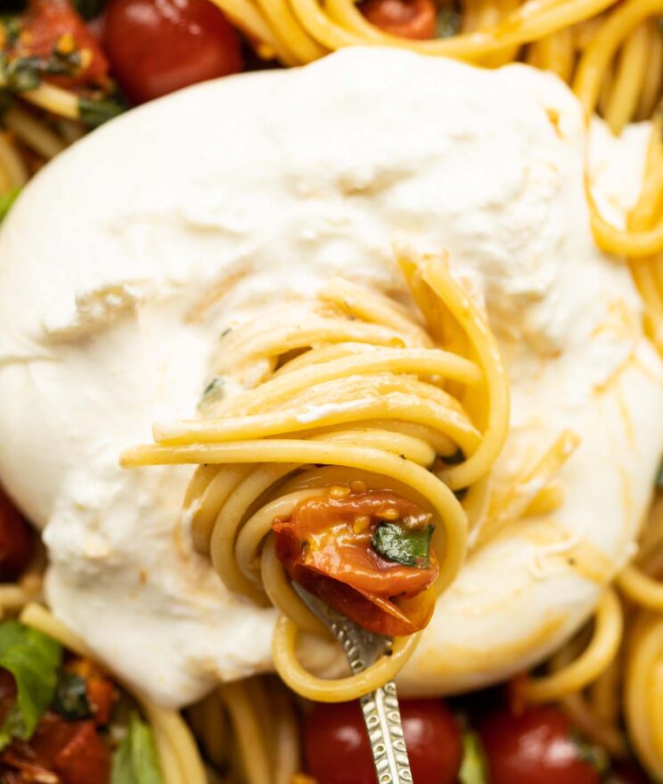 close up shot of silver fork twisting past in to burrata