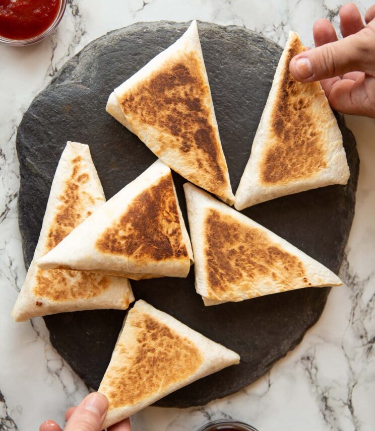overhead shot of 6 breakfast pockets on slate with two hands grabbing one each