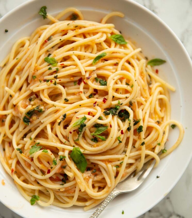 overhead shot of butter tomato pasta served in white dish with silver fork