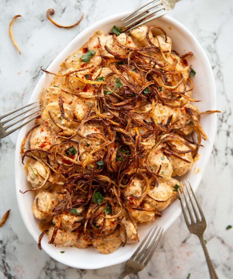 overhead shot of cajun potato salad in large white serving dish with 4 silver forks