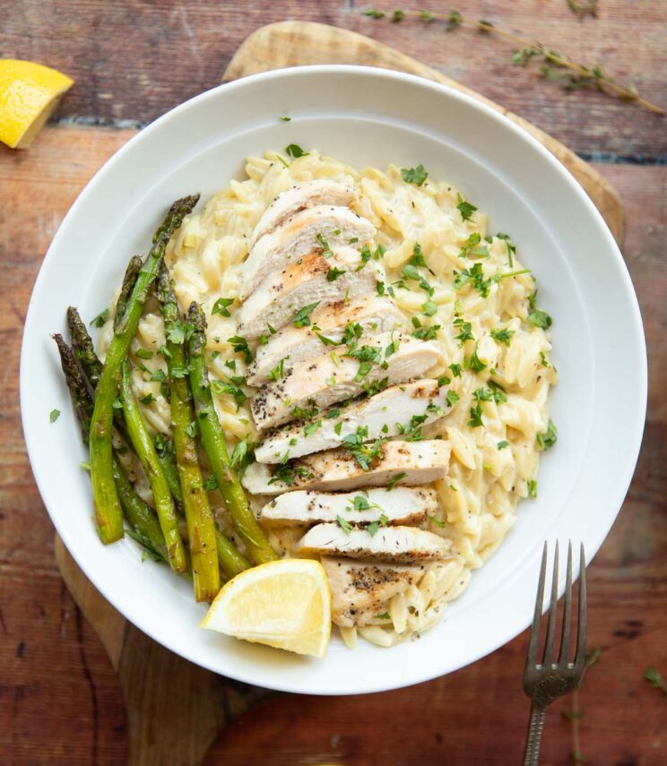 overhead shot of chicken and lemon orzo served in white bowl on wooden surface