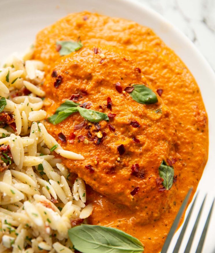 overhead shot of roasted red pepper chicken served on white plate with orzo