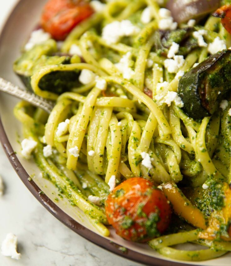 close up shot of silver fork twisting into plate of roasted veggie pesto pasta
