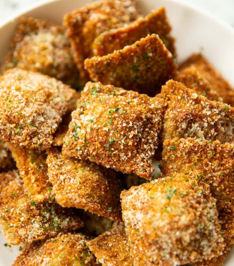 close up shot of toasted ravioli in large white dish