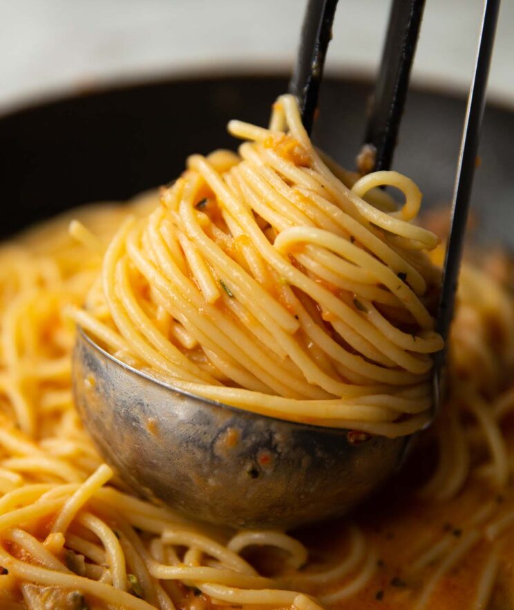 close up shot of tomato butter pasta in silver ladle