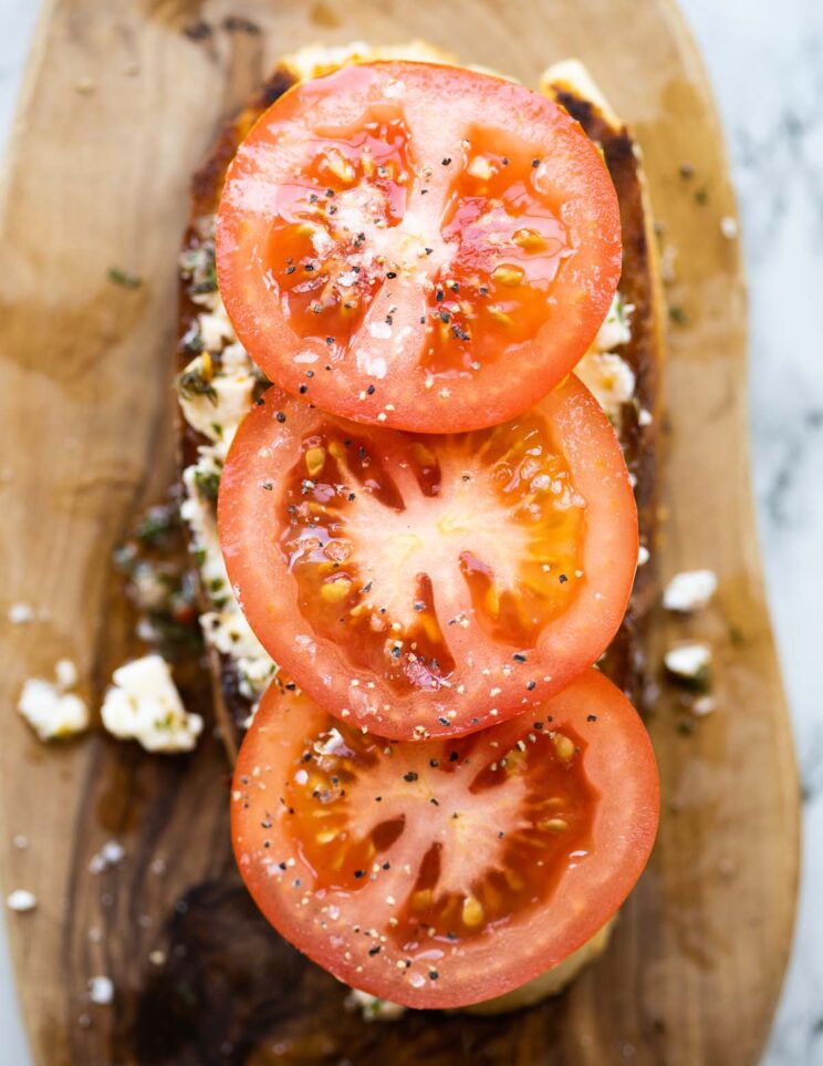 close up overhead shot of marinated feta on toast with sliced tomatoes