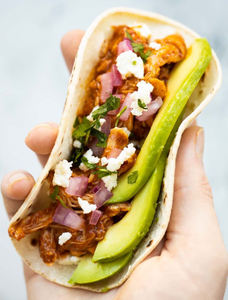 close up overhead shot of hand holding slow cooker chicken taco