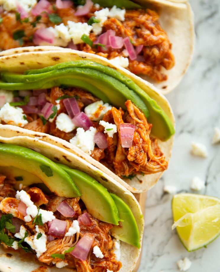 close up shot of 3 tacos side by side on marble backdrop