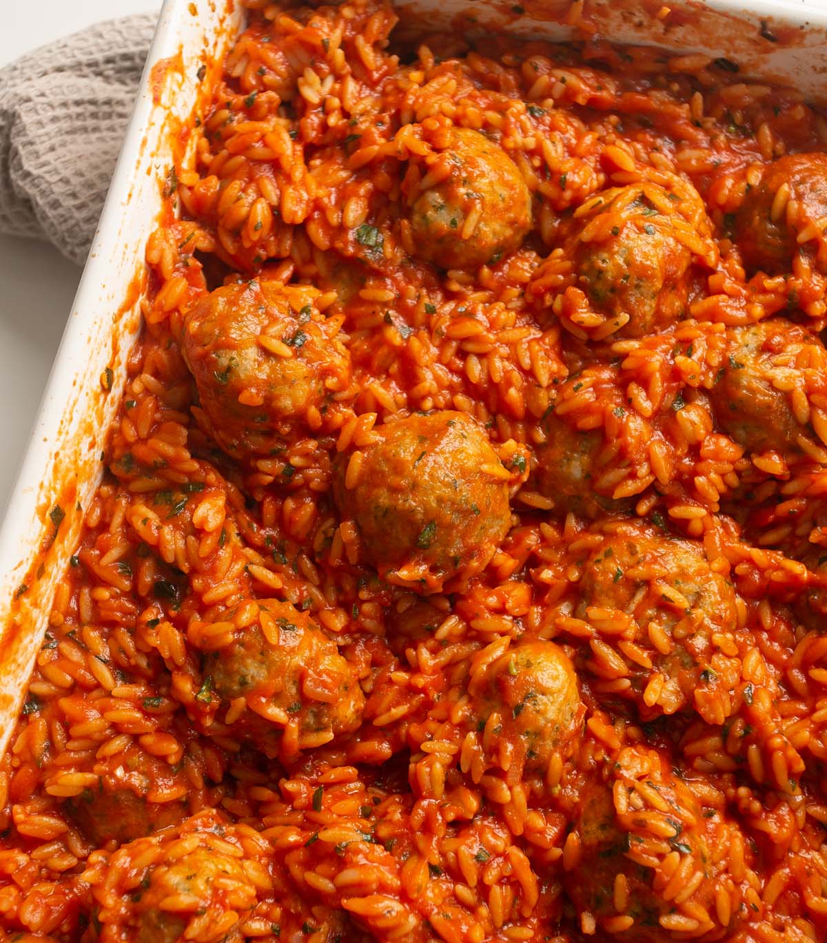 close up shot of baked meatballs orzo in large baking dish