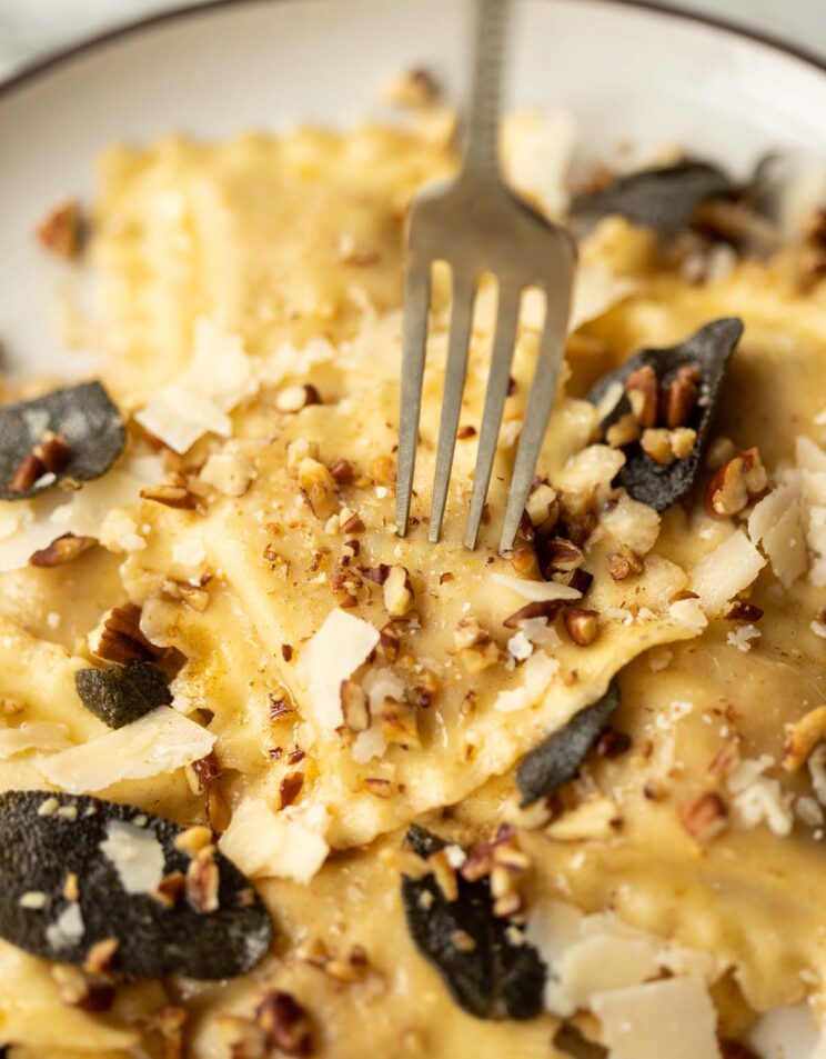 close up shot of silver fork digging into ravioli on plate