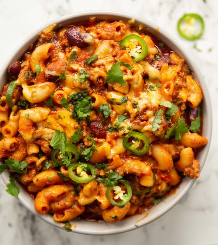close up overhead shot of chili mac and cheese served in grey bowl on marble backdrop