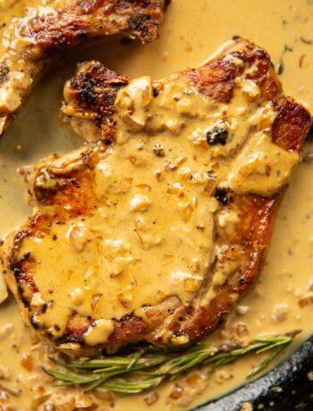 close up overhead shot of pork chop in garlic sauce in cast iron skillet