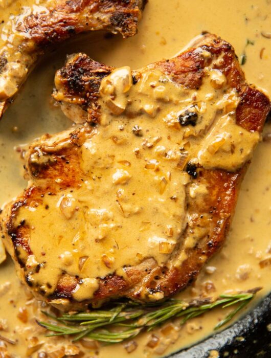 close up overhead shot of pork chop in garlic sauce in cast iron skillet