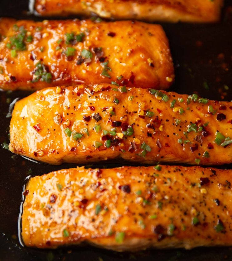 4 salmon fillets in pan garnished with spring onion and chilli flakes