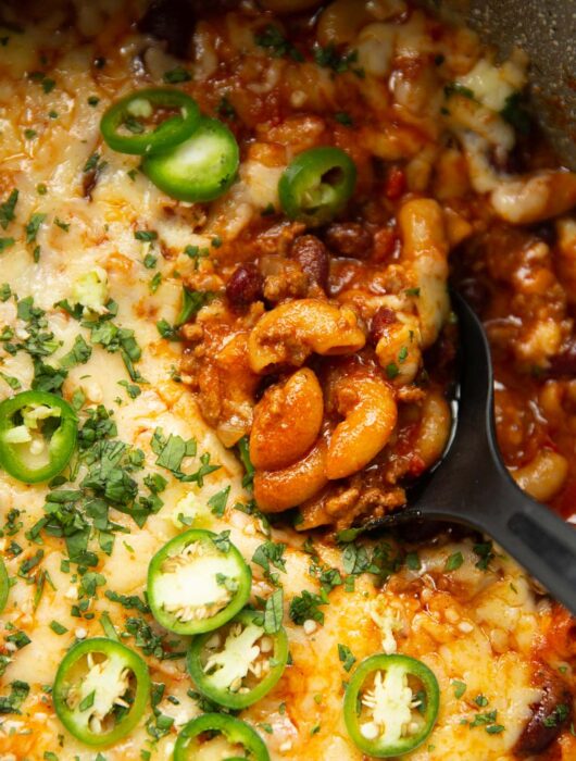 overhead close up shot of black serving spoon digging into pot of chili mac