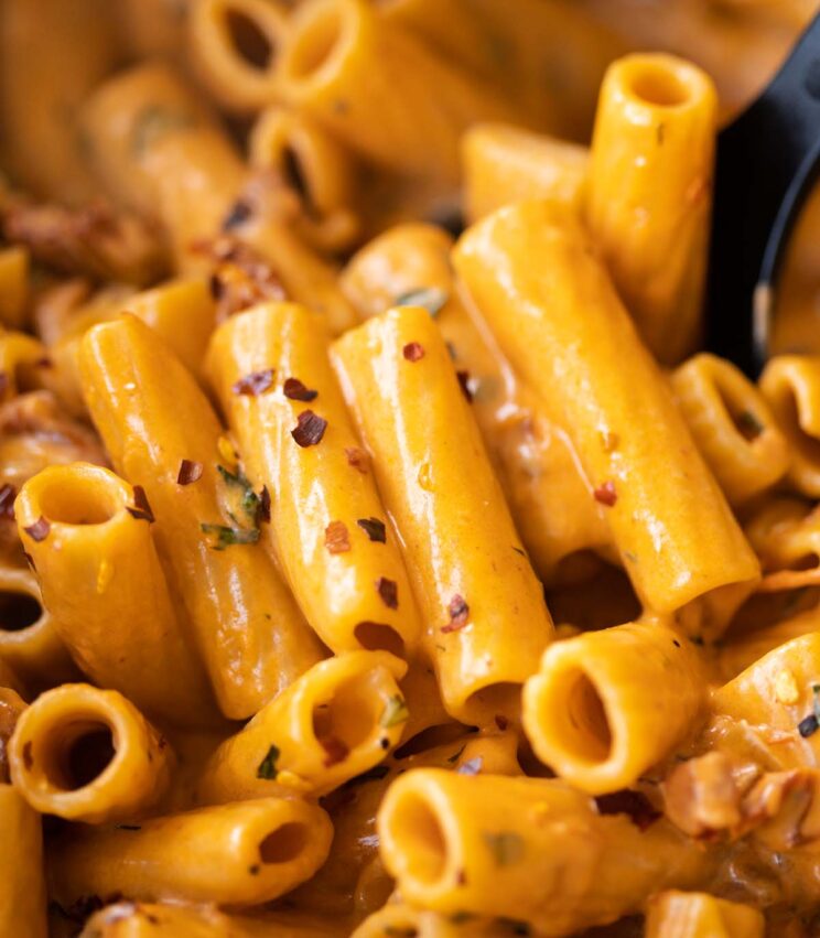 close up shot of spicy rigatoni in pot with serving spoon digging in