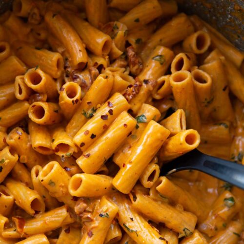 overhead shot of black serving spoon digging into pot of spicy rigatoni
