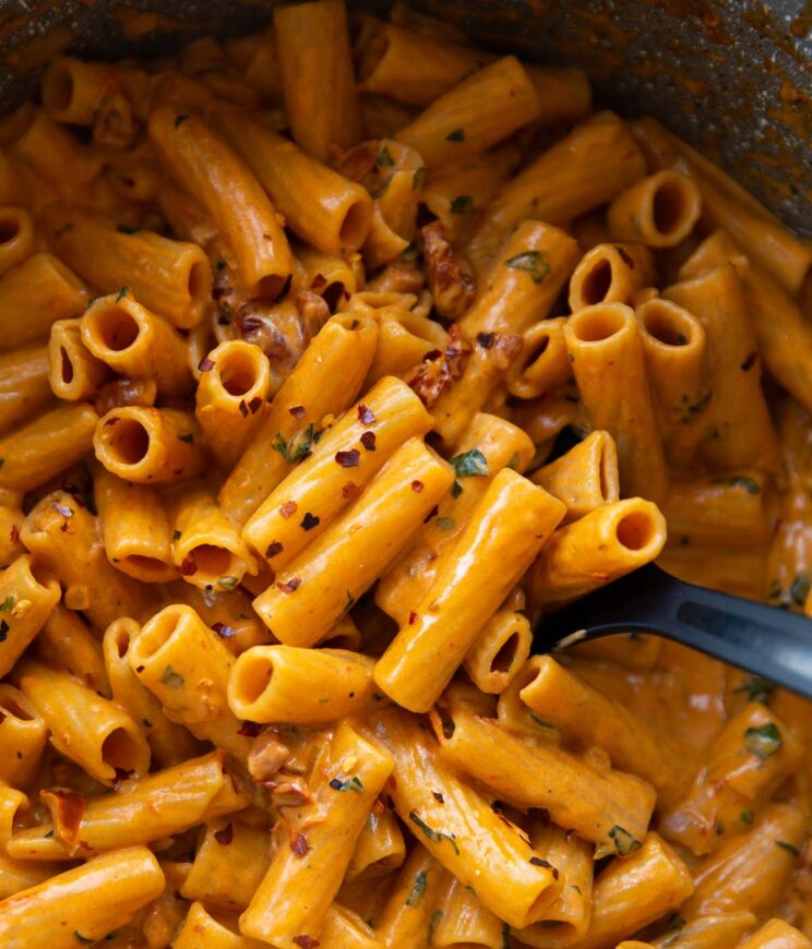 overhead shot of black serving spoon digging into pot of spicy rigatoni