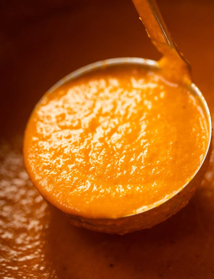 close up shot of roasted red pepper soup in ladle