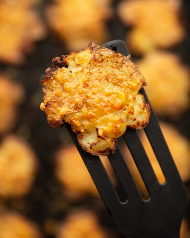 close up overhead shot of black spatula holding smashed potato above tray