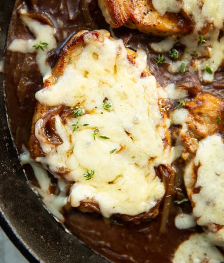 overhead shot of french onion pork chop in skillet with fresh thyme