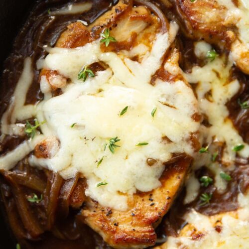 close up shot of french onion pork chop in skillet garnished with fresh thyme