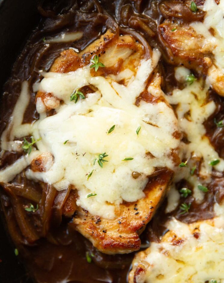 close up shot of french onion pork chop in skillet garnished with fresh thyme