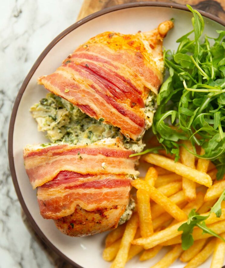 overhead shot of spinach artichoke chicken on white plate with fries and rocket