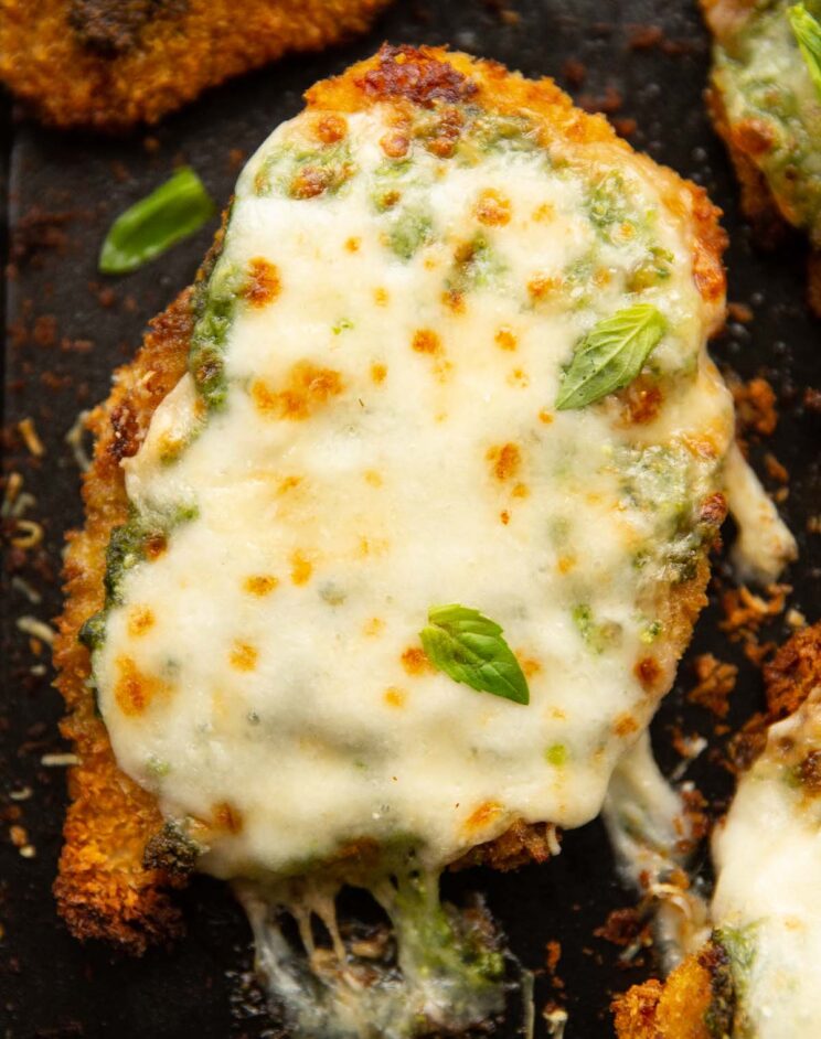 close up overhead shot of baked pesto chicken fresh out the oven on black baking tray